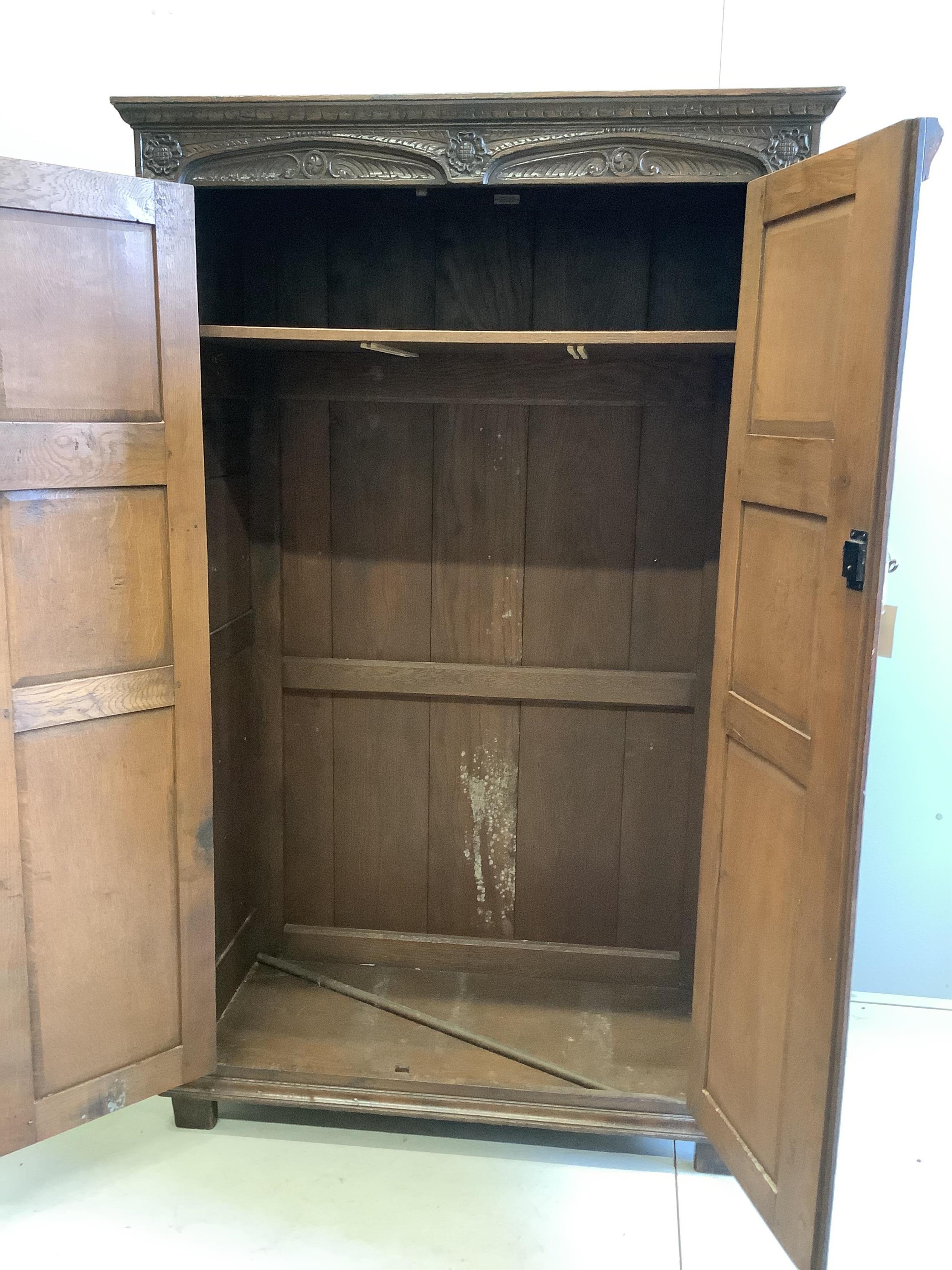 An 18th century style carved oak two door wardrobe, width 112cm, depth 57cm, height 183cm